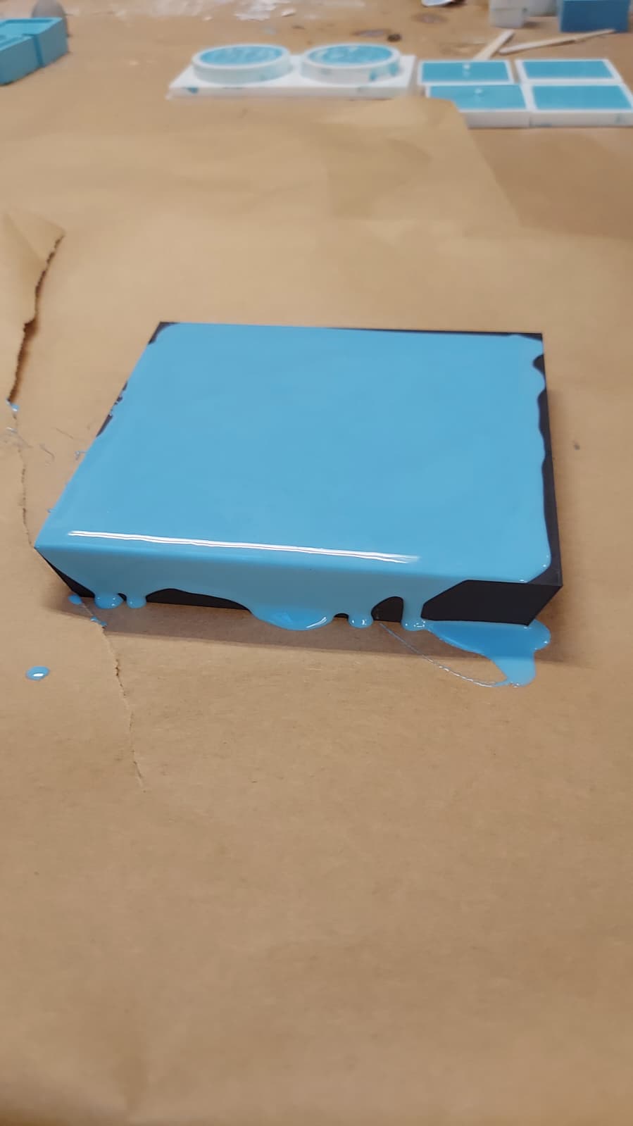 Blue silicone overflowing slightly from the sides of the frame onto paper
